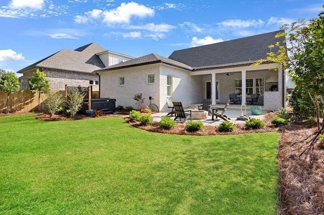 rear view of property with ceiling fan, an outdoor fire pit, a patio area, a hot tub, and a lawn