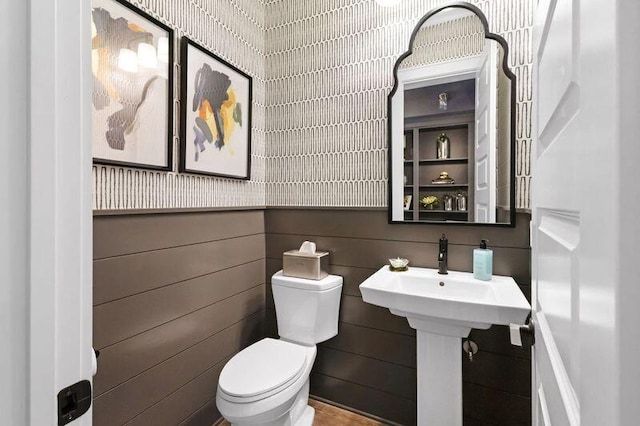 bathroom with wood walls and toilet