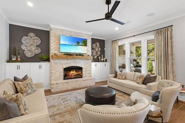 living room with ceiling fan, a fireplace, light hardwood / wood-style floors, and ornamental molding