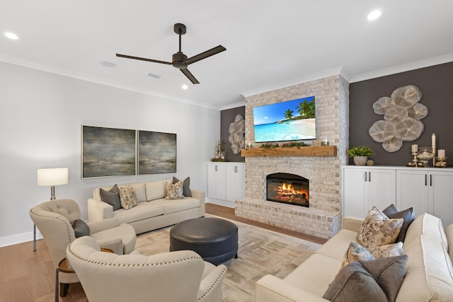 living room with a fireplace, light hardwood / wood-style floors, ceiling fan, and crown molding