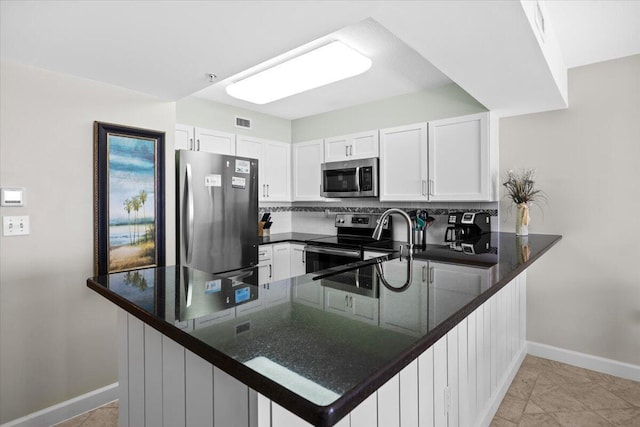 kitchen featuring kitchen peninsula, appliances with stainless steel finishes, white cabinets, and decorative backsplash