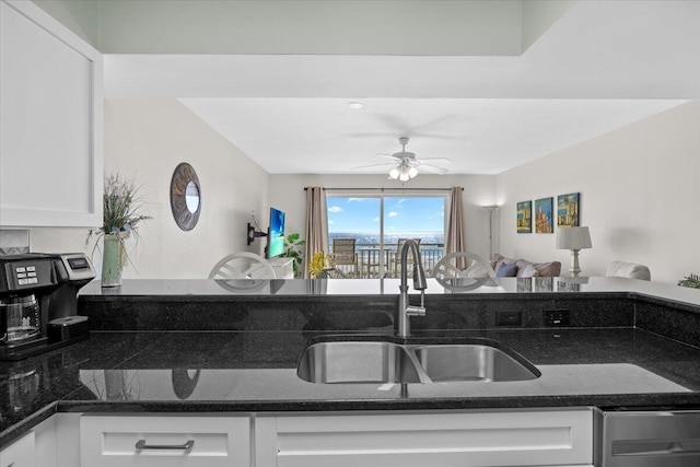 kitchen with dark stone countertops, white cabinetry, sink, and ceiling fan