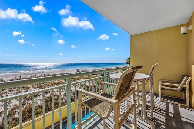 balcony featuring a view of the beach and a water view