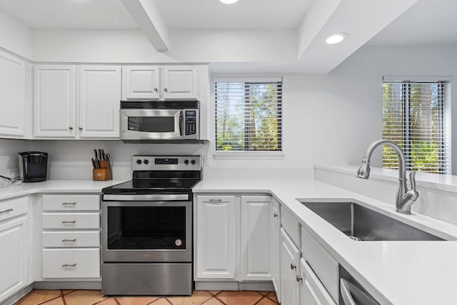 kitchen with light tile patterned floors, stainless steel appliances, white cabinetry, and sink