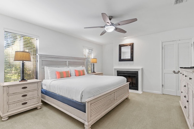 bedroom featuring ceiling fan, light colored carpet, and a closet