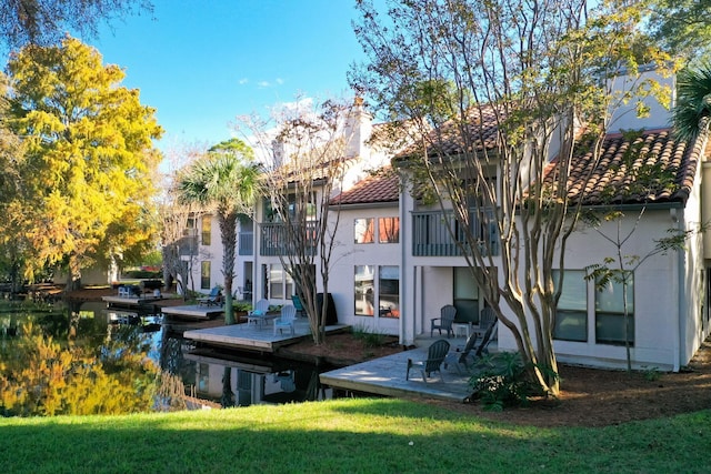 back of property featuring a lawn, a balcony, and a patio