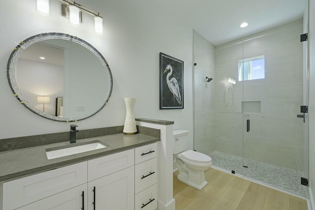 bathroom with a shower with door, hardwood / wood-style floors, toilet, and vanity