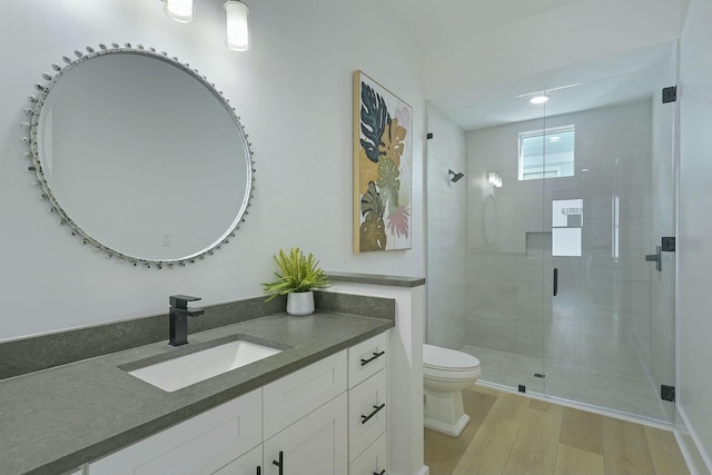 bathroom with toilet, a shower with shower door, hardwood / wood-style floors, and vanity