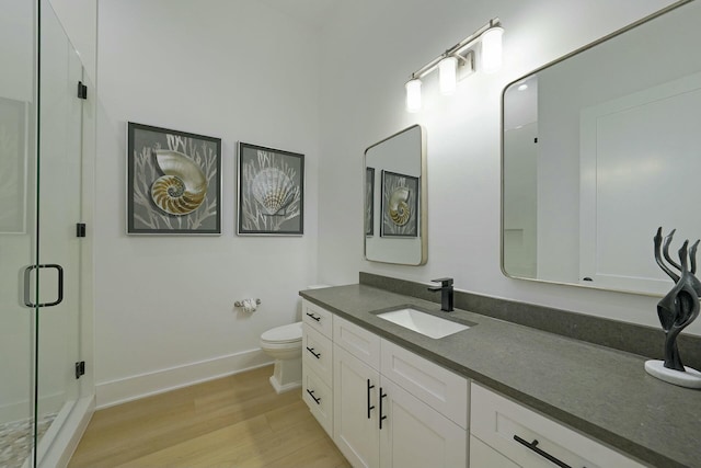 bathroom featuring toilet, vanity, a shower with door, and hardwood / wood-style floors