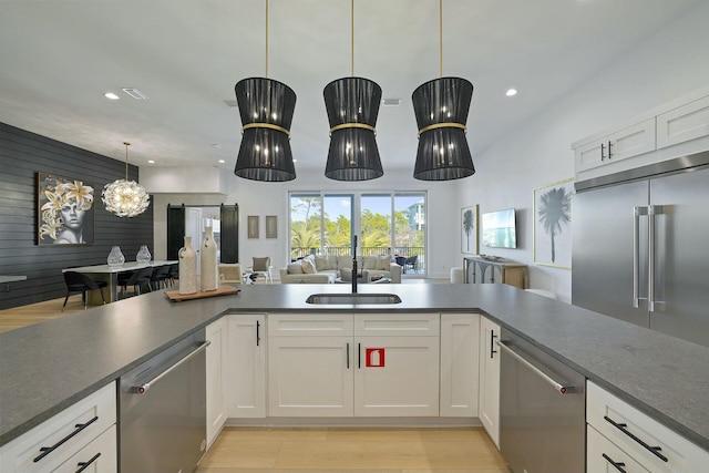 kitchen with hanging light fixtures, appliances with stainless steel finishes, sink, and white cabinetry