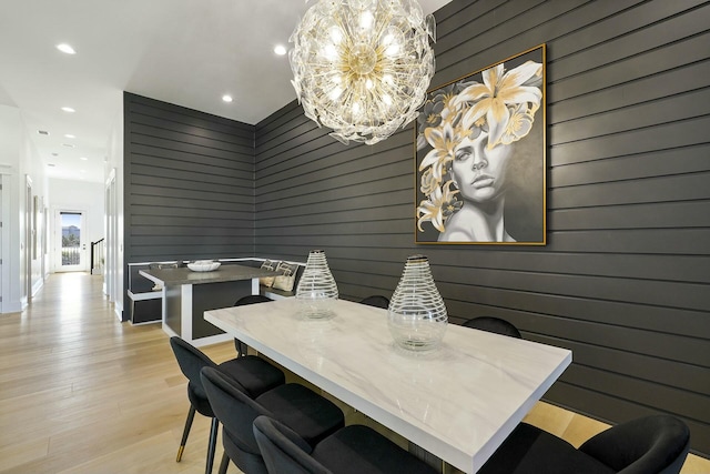 dining space with wood walls, a chandelier, and light hardwood / wood-style flooring