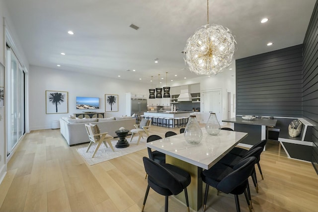 dining space with an inviting chandelier, plenty of natural light, and light hardwood / wood-style flooring