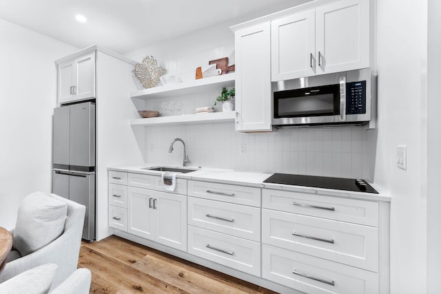 kitchen with sink, stainless steel appliances, backsplash, light hardwood / wood-style floors, and white cabinets