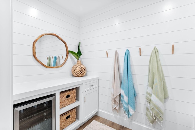 mudroom featuring wood walls, wine cooler, and light hardwood / wood-style flooring