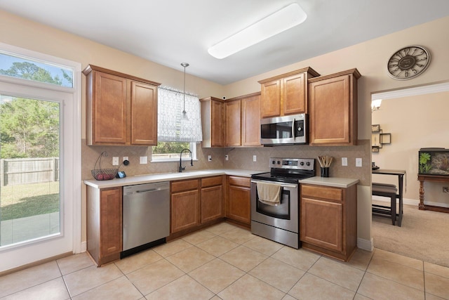 kitchen with sink, hanging light fixtures, decorative backsplash, light tile patterned floors, and appliances with stainless steel finishes