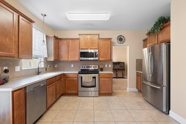 kitchen with sink, hanging light fixtures, tasteful backsplash, light tile patterned floors, and appliances with stainless steel finishes