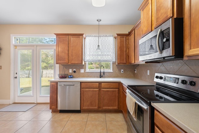 kitchen with a wealth of natural light, stainless steel appliances, hanging light fixtures, and sink