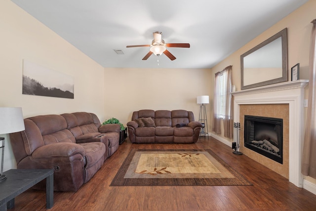 living room with a tile fireplace, ceiling fan, and dark hardwood / wood-style flooring