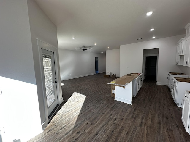 kitchen featuring dark wood-type flooring, ceiling fan, a center island, and white cabinets