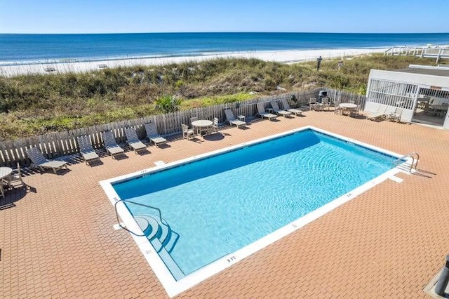 view of swimming pool with a view of the beach, a water view, and a patio area