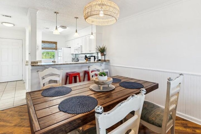 dining room with an inviting chandelier, ornamental molding, a textured ceiling, and hardwood / wood-style flooring