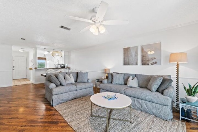 living room featuring wood-type flooring, a textured ceiling, and ceiling fan