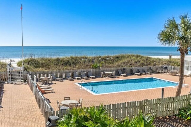 view of swimming pool featuring central AC, a water view, and a beach view