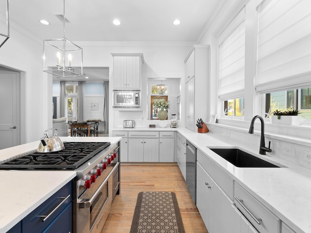 kitchen with sink, white cabinets, light wood-type flooring, and appliances with stainless steel finishes