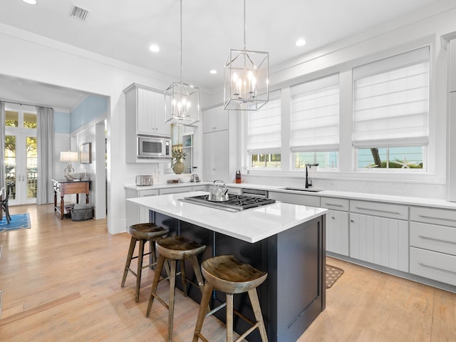 kitchen with appliances with stainless steel finishes, a kitchen island, plenty of natural light, and sink