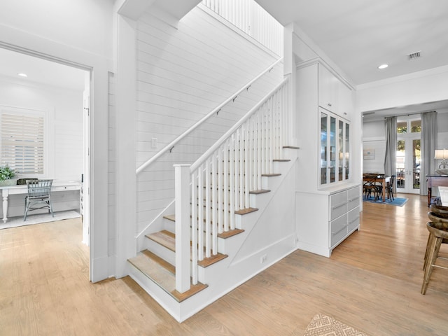 staircase with wood-type flooring and ornamental molding