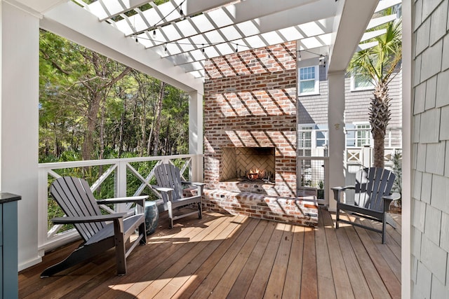 wooden deck featuring an outdoor brick fireplace and a pergola