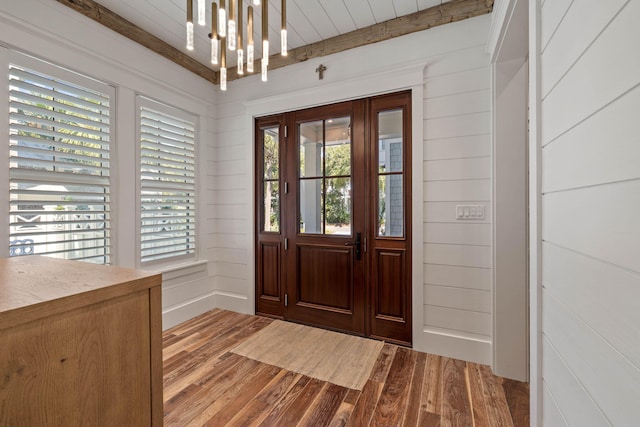 entrance foyer featuring a chandelier, wood walls, beam ceiling, and light hardwood / wood-style flooring