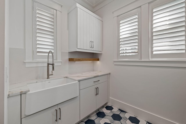 kitchen featuring white cabinets, light stone countertops, a healthy amount of sunlight, and sink