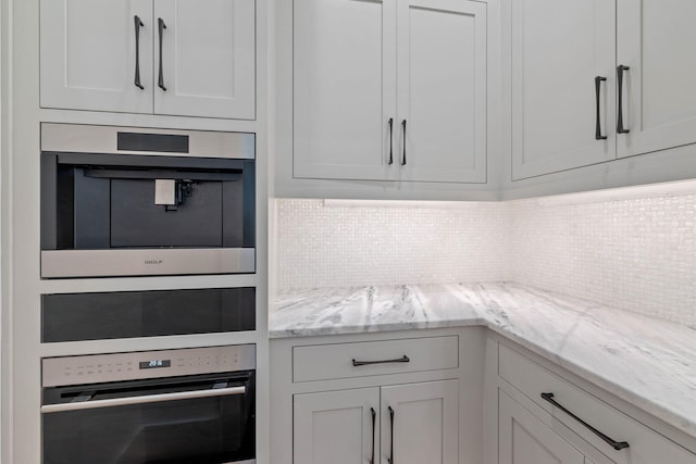 kitchen featuring white cabinets, oven, and light stone counters