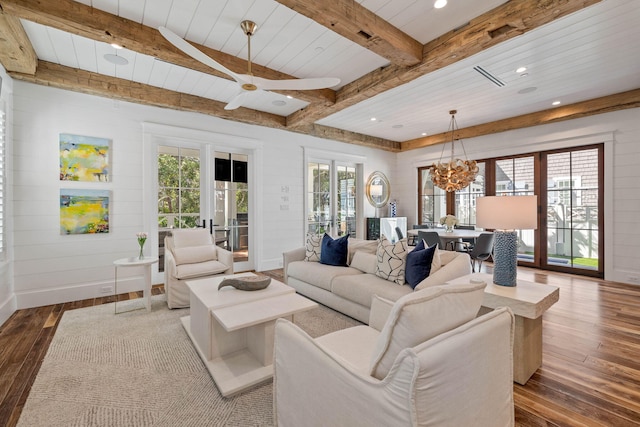 living room with beam ceiling, plenty of natural light, wood-type flooring, and ceiling fan with notable chandelier