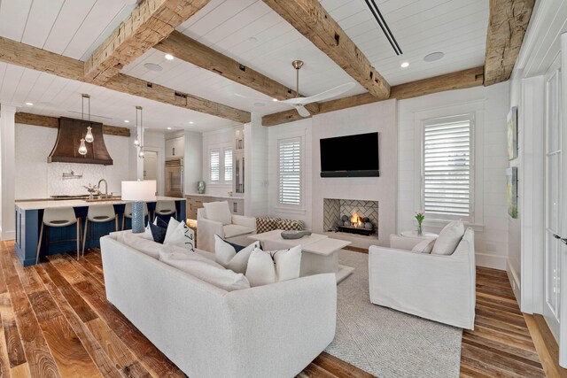 living room featuring beam ceiling, a wealth of natural light, and dark wood-type flooring