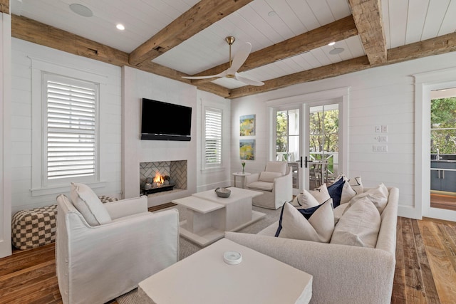 living room featuring hardwood / wood-style floors, plenty of natural light, a large fireplace, and beamed ceiling