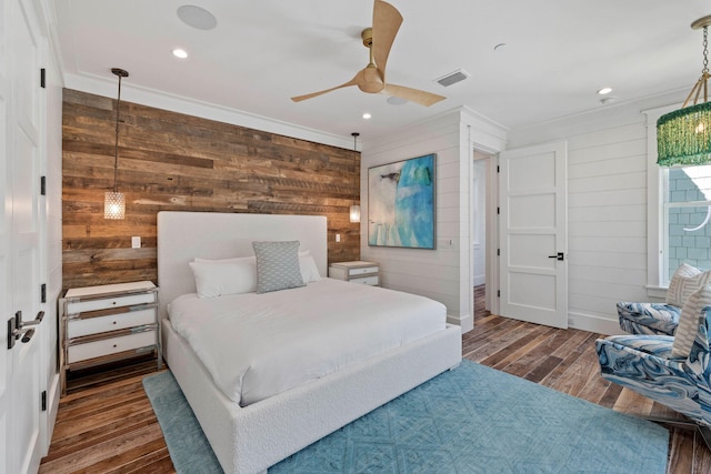 bedroom featuring ceiling fan, wood walls, dark hardwood / wood-style floors, and ornamental molding