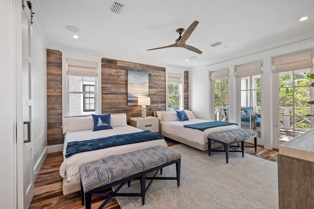 bedroom with multiple windows, wood-type flooring, and a barn door