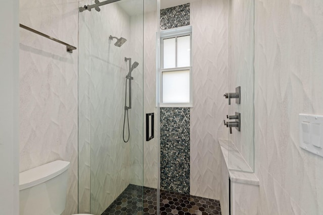 bathroom featuring toilet and a shower with shower door