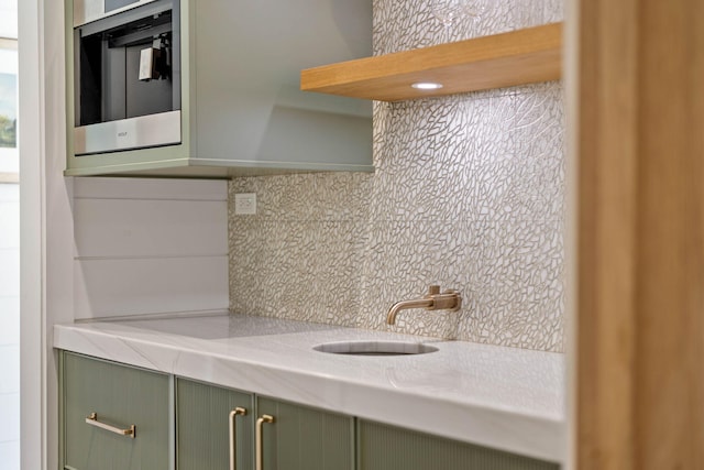 kitchen featuring tasteful backsplash, green cabinets, and sink