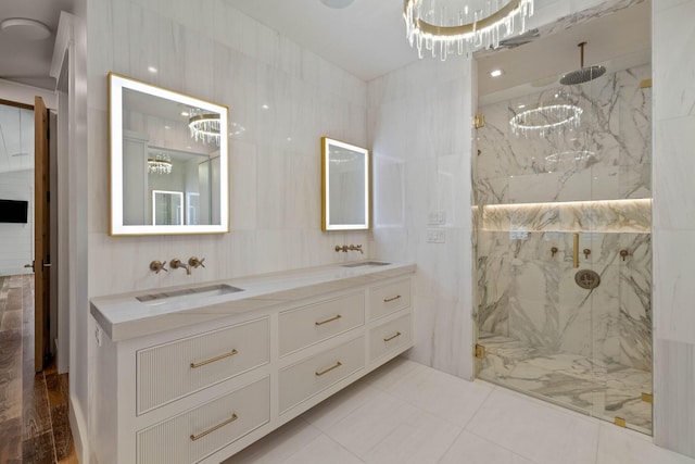 bathroom featuring a tile shower, a notable chandelier, tile patterned floors, vanity, and tile walls