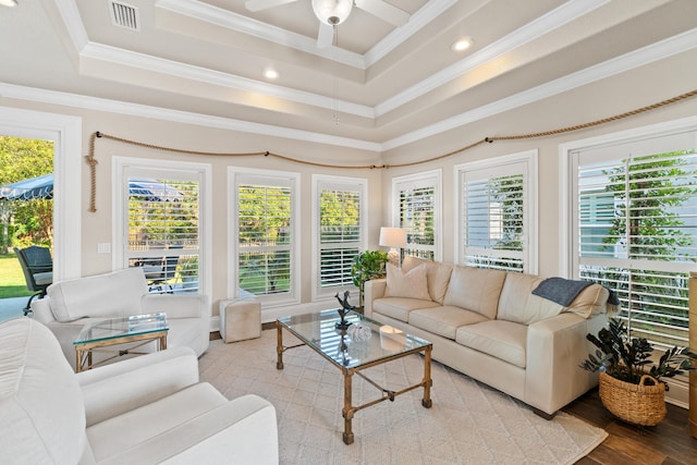 living room with a raised ceiling, crown molding, ceiling fan, and light wood-type flooring