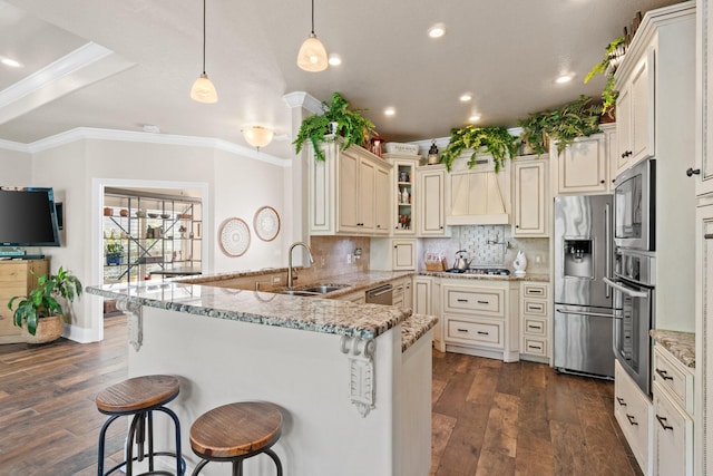 kitchen with sink, hanging light fixtures, dark hardwood / wood-style flooring, a breakfast bar area, and appliances with stainless steel finishes