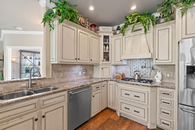 kitchen featuring appliances with stainless steel finishes, backsplash, premium range hood, sink, and cream cabinets