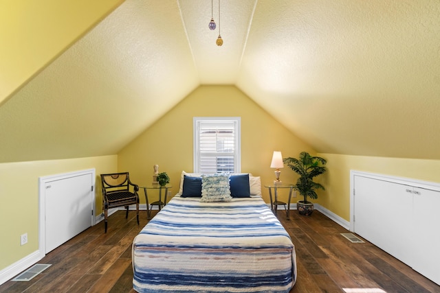 bedroom with a textured ceiling, vaulted ceiling, and dark wood-type flooring