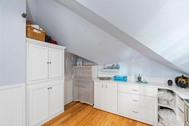 interior space with white cabinets, light wood-type flooring, and lofted ceiling