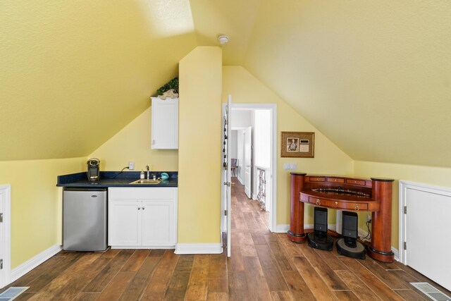 kitchen with stainless steel fridge, dark hardwood / wood-style flooring, vaulted ceiling, sink, and white cabinets