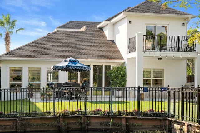 back of house with a balcony and a yard