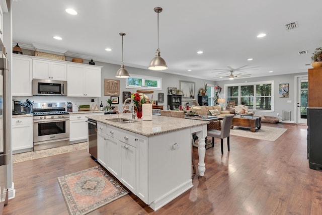 kitchen featuring a kitchen island with sink, sink, ceiling fan, appliances with stainless steel finishes, and decorative light fixtures